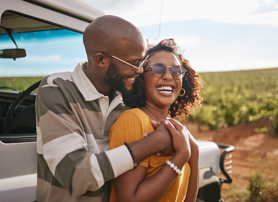 Read Our Reviews - Closeup View of a Cheerful Young Couple Standing Next to Their Jeep While Parked in the Countryside During a Road Trip on a Sunny Afternoon